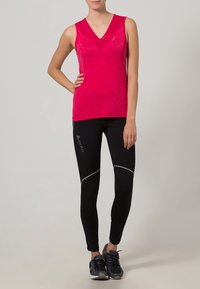 Różowy bezrękawnik sportowy z dekoltem w serek, w zestawie z czarnymi dopasowanymi legginsami z szarym przeszyciem i detalem z logo.
