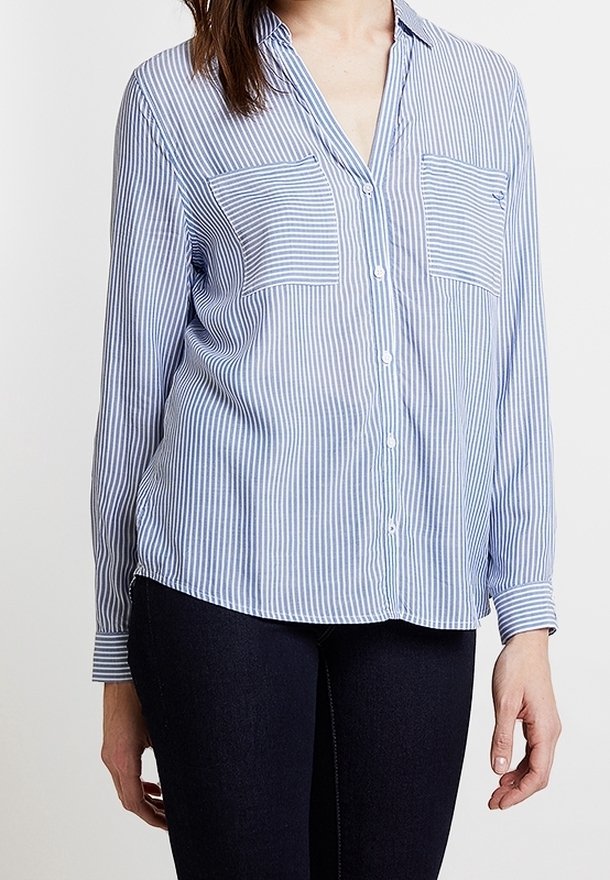 Chemise à boutons rayée en bleu clair et blanc. Comprend deux poches poitrine, des manches longues et une coupe décontractée. Texture de tissu lisse.
