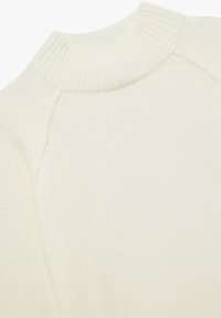 Cremefarbener Pullover mit geripptem Stehkragen, weicher Textur und Raglanärmeln. Der Stoff sieht leicht und glatt aus.