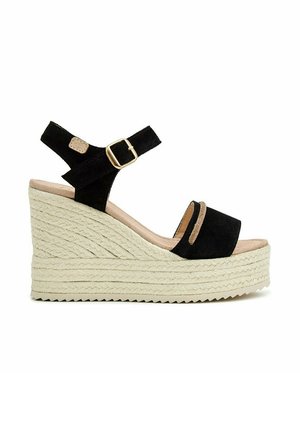 Sandalia de cuña negra de ante con plataforma de cuerda beige, correa de tobillo con hebilla dorada y diseño de punta abierta.