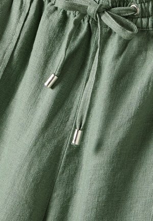 Green linen shorts featuring an elastic waistband with a drawstring finished with silver metal aglets. Textured fabric with a natural look.