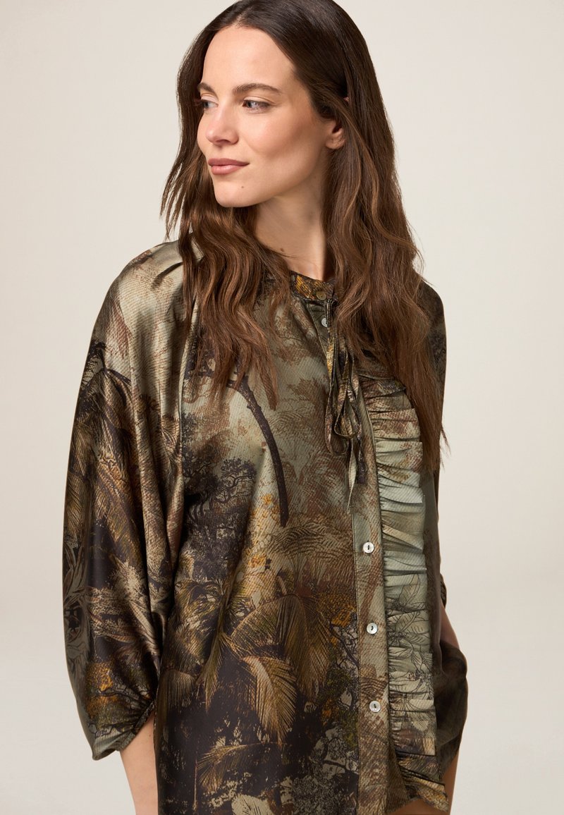 Jedwabna koszula z nadrukiem inspirowanym naturą w ziemistych odcieniach, z zapięciem na guziki z przodu, marszczonymi detalami i szerokimi rękawami.
