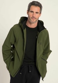 Oliven grøn, vandtæt jakke med sort hætte og foring, som har en for-zipper, sidelommer og justerbare manchetter.