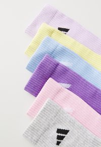 Juego de seis diademas de algodón con relieve en colores: lavanda, amarillo, azul claro, púrpura, rosa y gris, cada una con un detalle del logo en negro.