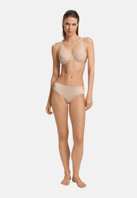 Completo intimo beige composto da un reggiseno in pizzo con motivo floreale e ferretto, abbinato a slip bikini lisci.