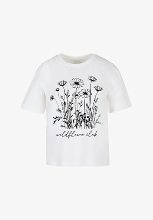 Hvit bomullst-skjorte med svart blomstertrykk og teksten "wildflower club" nedenfor. Kombinert med lyseblå skinny jeans og hvite sneakers.