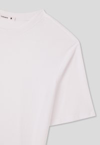 T-shirt bianco a maniche corte realizzato in cotone, con un colletto a girocollo a coste e una texture liscia, con un'etichetta che indica la taglia S.