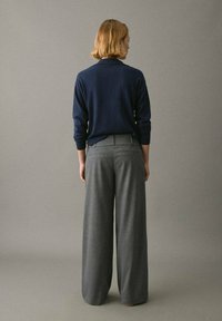 Camiseta de punto azul marino de manga larga con cuello, combinada con pantalones anchos grises. Textura suave, corte relajado y diseño minimalista.