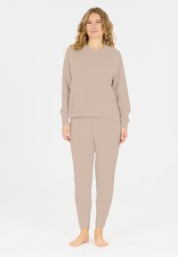 Beige loungemodeset met een sweatshirt met lange mouwen en een ronde hals, en slim-fit broek, met een zachte textuur en een casual ontwerp zonder patronen.