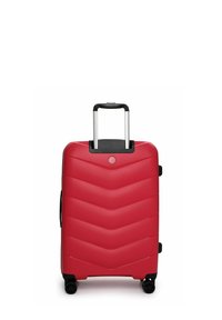 Červený kufr s tvrdou skořepinou a vzorem ve tvaru šípu, prodloužená stříbrná rukojeť a čtyři černá kolečka pro snadnou mobilitu. Hladký povrch.