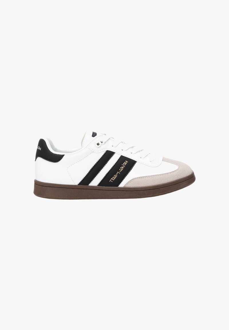 Zapato deportivo blanco con rayas negras, con puntera de ante gris y suela de goma marrón. Cuenta con un diseño de cordones y una marca en el costado.