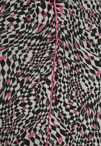 Svart och vit mönstrad tyg med ett virvlande mönster, som har rosa detaljer och en strukturerad, rynkad yta. Märkesdetaljer är framträdande genom hela designen.