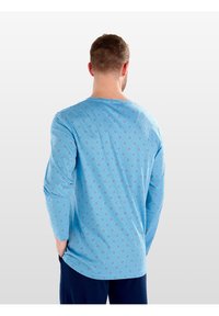 Maglietta a maniche lunghe blu con un motivo geometrico di un blu più chiaro. Texture morbida, scollatura rotonda e vestibilità rilassata.