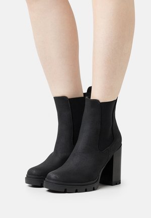 Botas negras hasta el tobillo de ante, con tacón cuadrado y paneles laterales elásticos. Punta redondeada y suela texturizada.