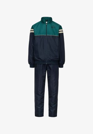 Tuta navy con un design a blocchi di colore teal e crema, composta da una giacca con zip e pantaloni coordinati, realizzata in materiale leggero e liscio.