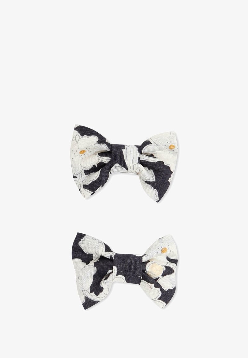 Deux nœuds en tissu pour cheveux, l'un blanc avec un motif floral noir et l'autre bleu marine uni, tous deux présentant une forme de nœud classique et une finition texturée.