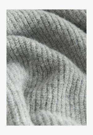 Lysegrå strikket stof med en ribbet tekstur, der har bløde, fnugget fibre og et bølget, draperet udseende.