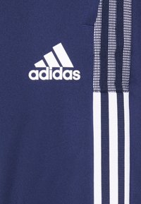 Donkerblauw sportshirt met een witte Adidas-logo en drie verticale witte strepen langs de zijkant, textiele stof met een dichtgeweven patroon.