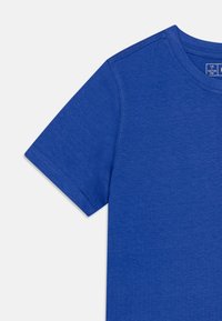 T-shirt en coton bleu à manches courtes, avec col rond et texture lisse. Étiquette visible indiquant la taille 7/8 (123/128 cm).
