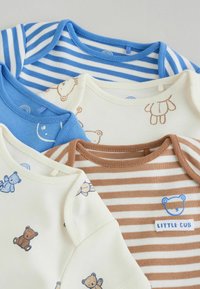 Pet malih presavijenih bodija za bebe u plavim i smeđim nijansama, s prugama i uzorkom medvjedića, jedan s natpisom "Mali mladunče".