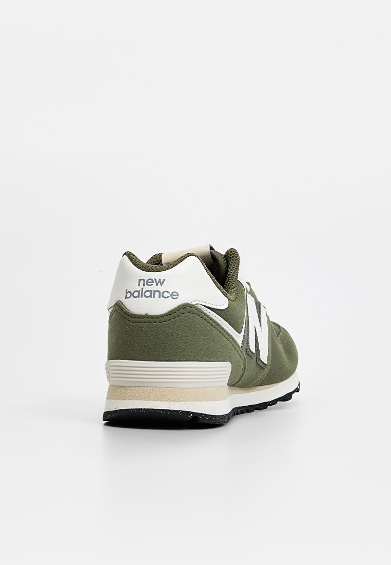 Baskets en suède vert avec des accents blancs, présentant un logo "N" bien visible, une semelle rembourrée et un revêtement texturé au niveau du talon.
