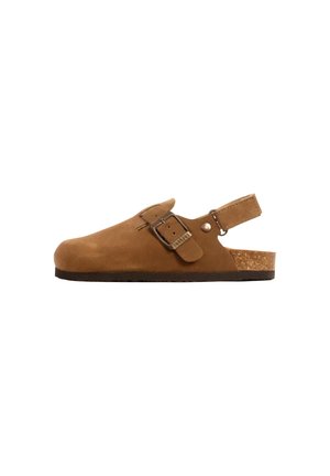 Sabot en daim marron avec bride à boucle réglable, dos ouvert avec bride au talon et semelle intérieure en liège sur une semelle plate noire.