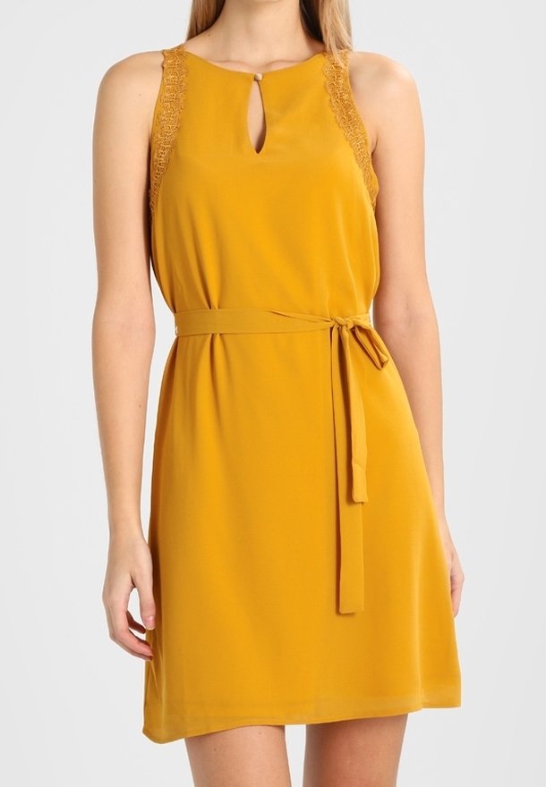 Robe jaune moutarde sans manches avec bordure en dentelle aux épaules, encolure goutte d'eau avec bouton et ceinture nouée à la taille.