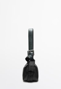 Sac à main en cuir noir avec un fond arrondi, une seule sangle ajustable et une boucle en argent. Texture lisse avec des détails de couture visibles.