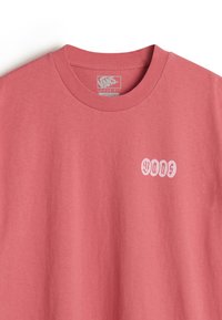 Lyserød bomulds T-shirt i løs pasform med rund halsudskæring, som har et lille hvidt "Vans" logo på venstre brystområde. Glat tekstur.
