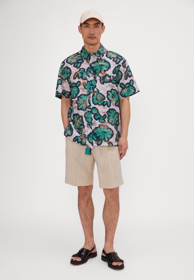 Short-sleeve shirt with a colorful floral pattern in green and blue, paired with beige shorts and black sandals. Neutral cap completes the look.