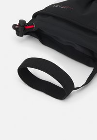 Schwarze Softshell-Tasche mit strukturierter Oberfläche, ausgestattet mit einem roten Kordelzugverschluss und einem schwarzen elastischen Griff für einen einfachen Transport.