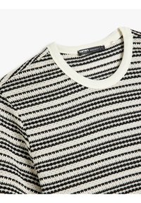 Suéter de punto a rayas en negro y crema, con cuello redondo acanalado. La textura es suave con rayas horizontales en varias dimensiones.