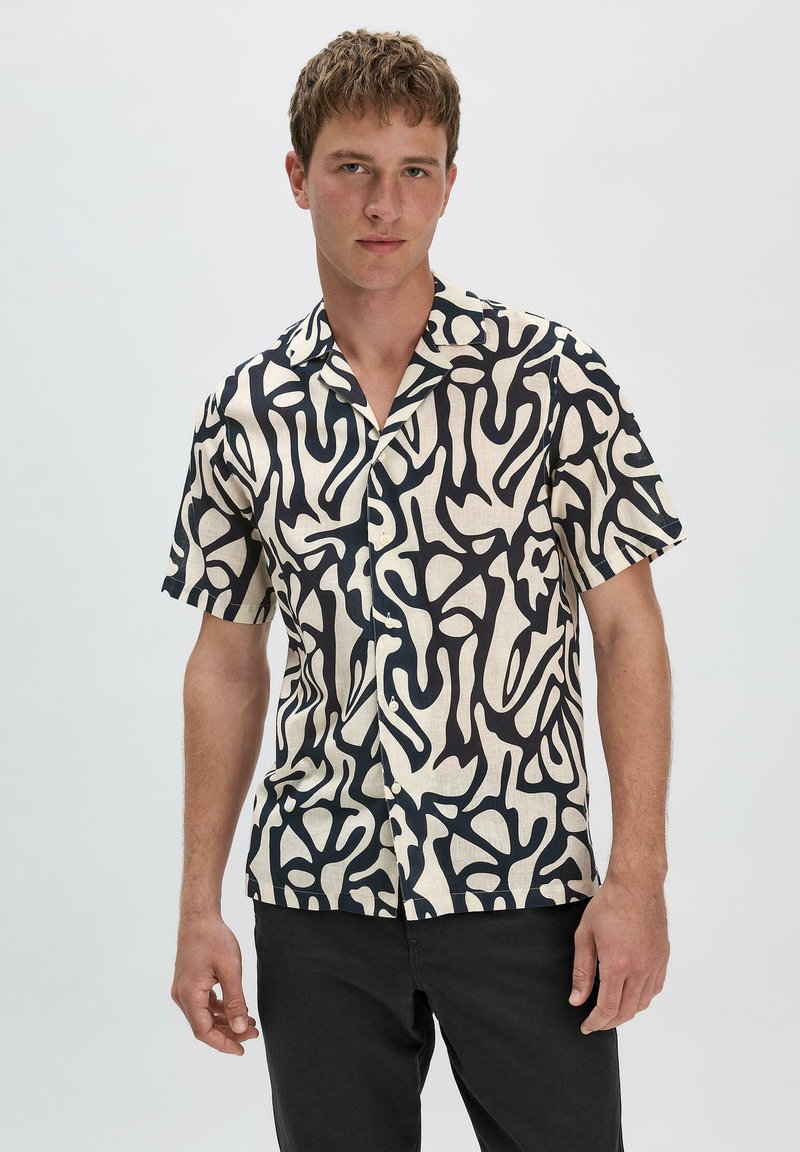 Korte mouwen shirt van crèmekleurige stof met een gedurfde zwarte abstracte print, met knopen aan de voorkant en een relaxte pasvorm.