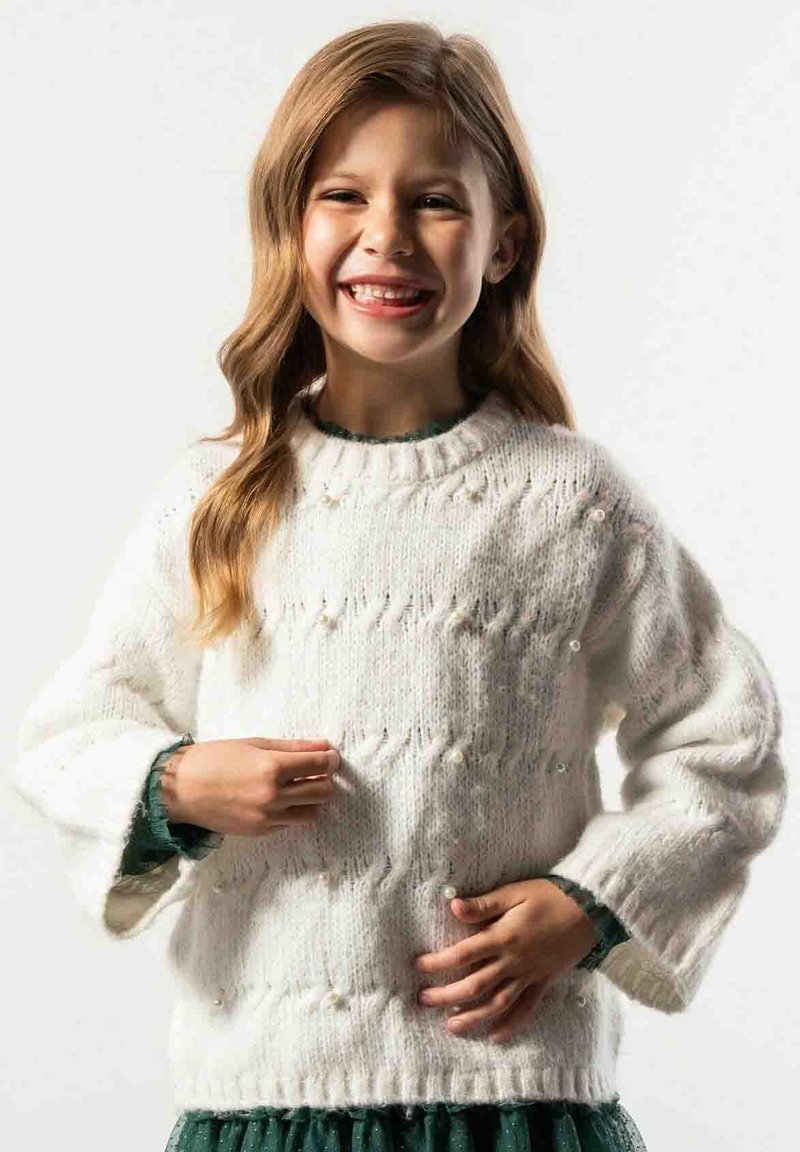 Biały sweter z dzianiny o luźnym kroju, teksturowanym wzorem ściegów i perłowymi ozdobami. Długie rękawy i ściągacz u dołu uzupełniają projekt.