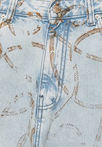 Blujeansi din denim de un albastru deschis, cu un model subtil de funie maro. Materialul are o textură ușor uzată, cu un nasture metalic și inchidere cu fermoar.