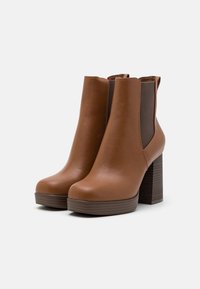 Brown leather ankle boots with elastic side panels, rounded toe, and a stacked wooden heel. Smooth texture, platform sole design.
