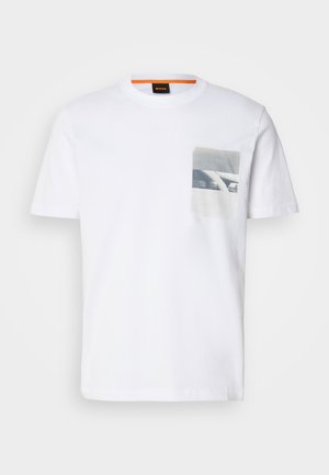 T-shirt en coton blanc avec un imprimé graphique de poche carrée en noir et blanc. Col rond et manches courtes.
