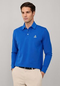 Langärmliges Polohemd aus leuchtend blauem Baumwollstoff, mit klassischem Kragen und kleinem besticktem Logo auf der Brust. Taillierte Passform.