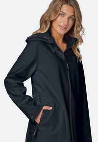 Tmavě modrá softshell bunda s předním zipem, nastavitelnou kapucí, bočními kapsami a kontrastními kovovými doplňky. Hladká textura a přiléhavý střih.