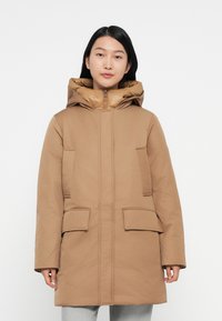 Bruine gewatteerde parka met een grote capuchon, twee voorzakken en een rits. Glad textuur, met een contrasterende binnenvoering.