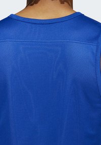 Man med en blå andningsbar mesh sporttröja som visar den övre delen av ryggen och nackområdet.