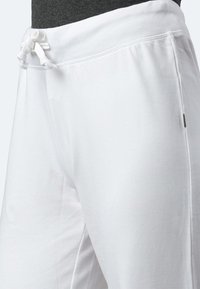 Weiße Baumwollsweatpants mit einem elastischen Bund und Kordelzug sowie seitlichen Taschen. Glatte Textur mit lockerer Passform.