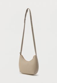 Μικρό μπεζ δερμάτινο τσαντάκι ώμου με ρυθμιζόμενο λουράκι και χρυσοφίγουρα φερμουάρ, σε απλό λευκό φόντο.