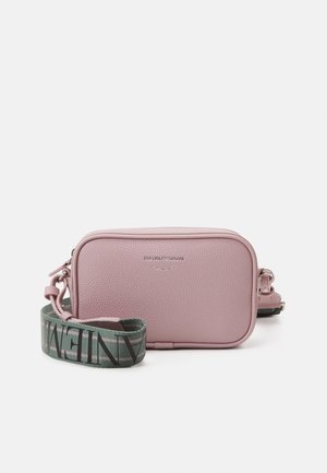 Sac en bandoulière en cuir texturé rose avec une sangle verte détachable, comportant des lettres noires et un logo embossé sur le devant.
