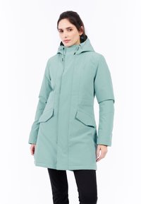 Vattentät tealjacka med huva, med frontdragkedja, två stora framfickor och medellång design. Slät textur och minimala detaljer.