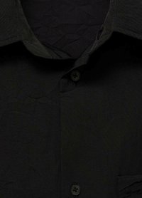 Schwarze Hemdjacke mit einem strukturierten, zerknitterten Stoff. Verfügt über einen klassischen Kragen, schwarze Knöpfe und eine einzelne Brusttasche.