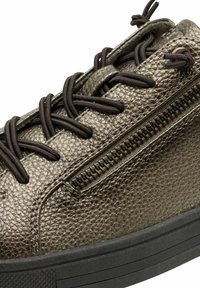 Baskets en bronze métallisé avec une surface texturée, lacets noirs et une fermeture éclair sur le côté. Présentent une semelle en caoutchouc et un design profil bas.