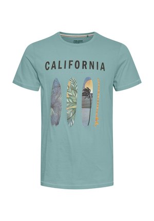 Hele sinine T-särk teksti "CALIFORNIA SURFING COMPANY" ja nelja värvilise lainelaudade illustratsiooniga esiküljel.