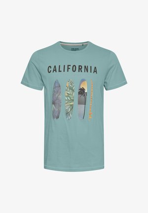 Hele sinine T-särk teksti "CALIFORNIA SURFING COMPANY" ja nelja värvilise lainelaudade illustratsiooniga esiküljel.