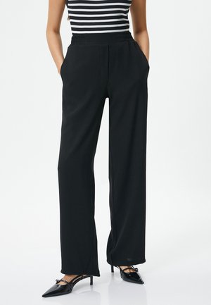 Zwarte wijde broek met een elastische taille, voorzien van zijzakken en een soepele, lichtgewicht stof. Gepaard met puntige hakschoenen.